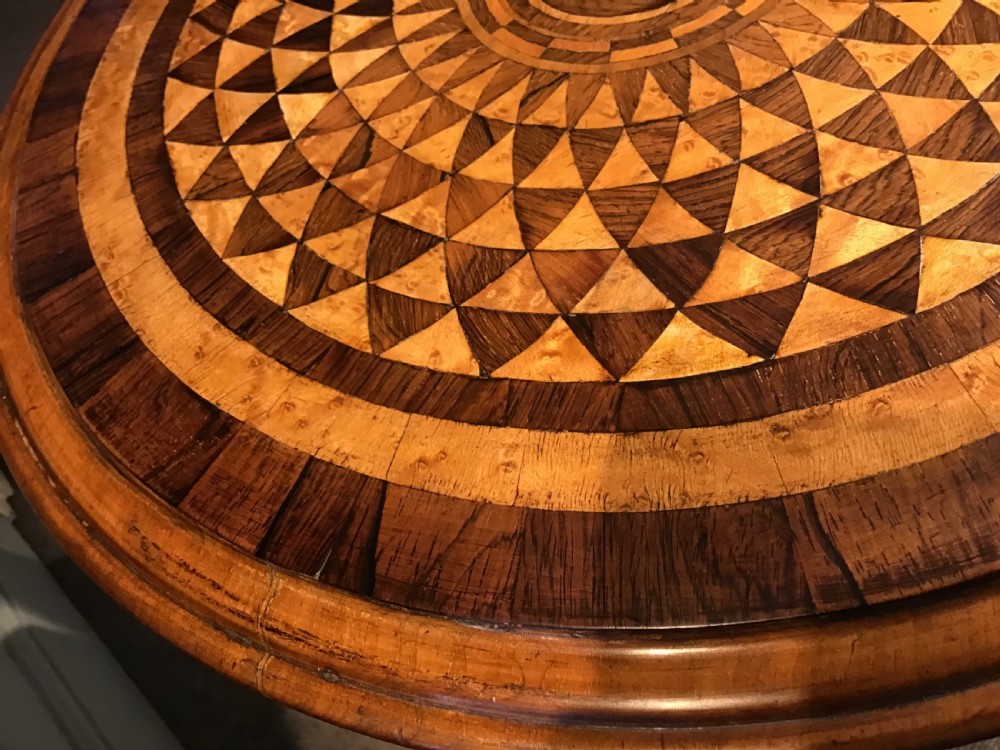 A Victorian tripod occasional table with a circular top featuring geometric specimen wood marquetry and a turned pedestal column. View III