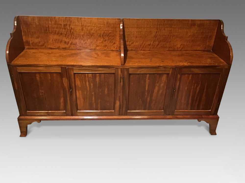 An antique mahogany side cabinet featuring a two-section top gallery, four panelled doors, and standing on bracket feet.