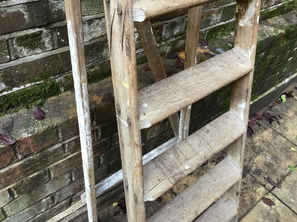 A tall weathered wooden A-frame stepladder featuring a slatted top platform and multiple flat treads. View IV