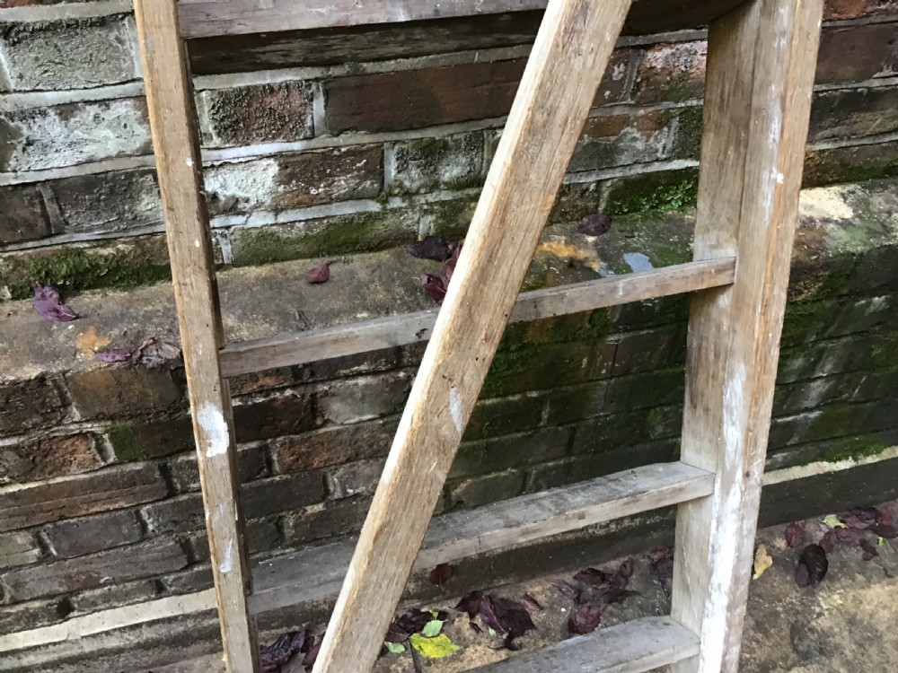 A tall weathered wooden A-frame stepladder featuring a slatted top platform and multiple flat treads. View IX