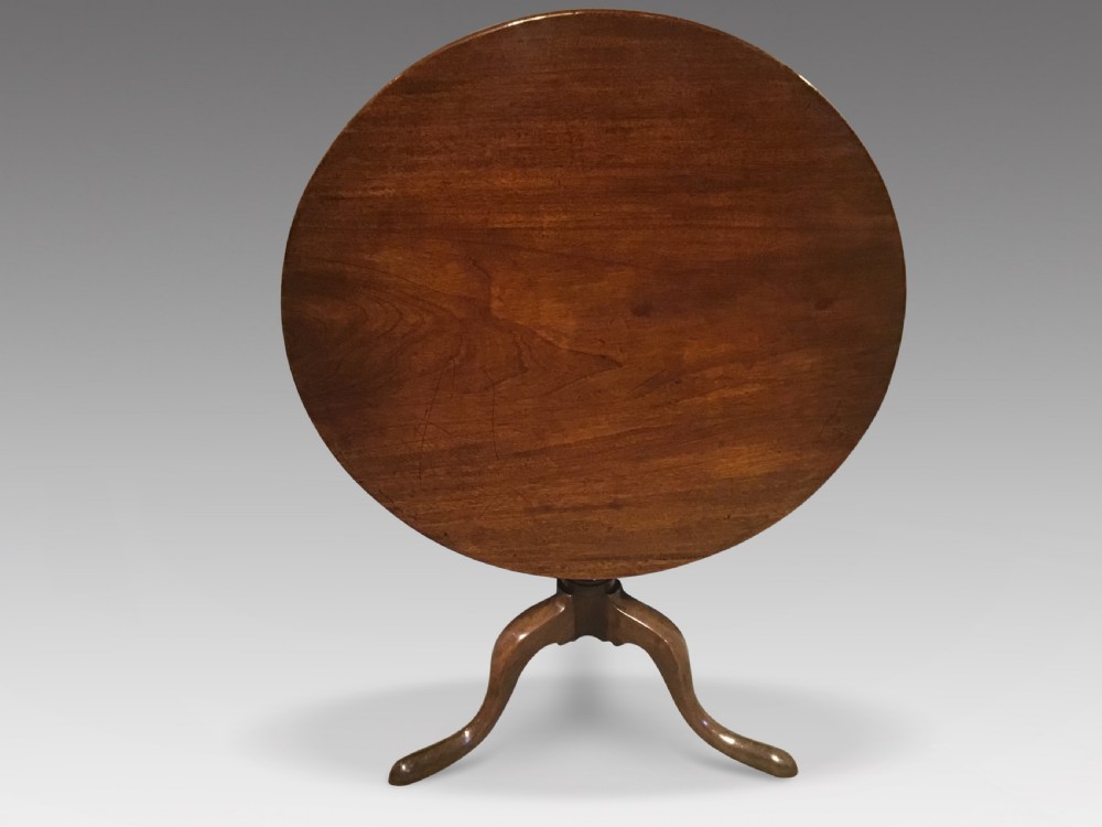 A Georgian mahogany tripod table with a circular tilt-top raised on a turned central pedestal and three cabriole legs.