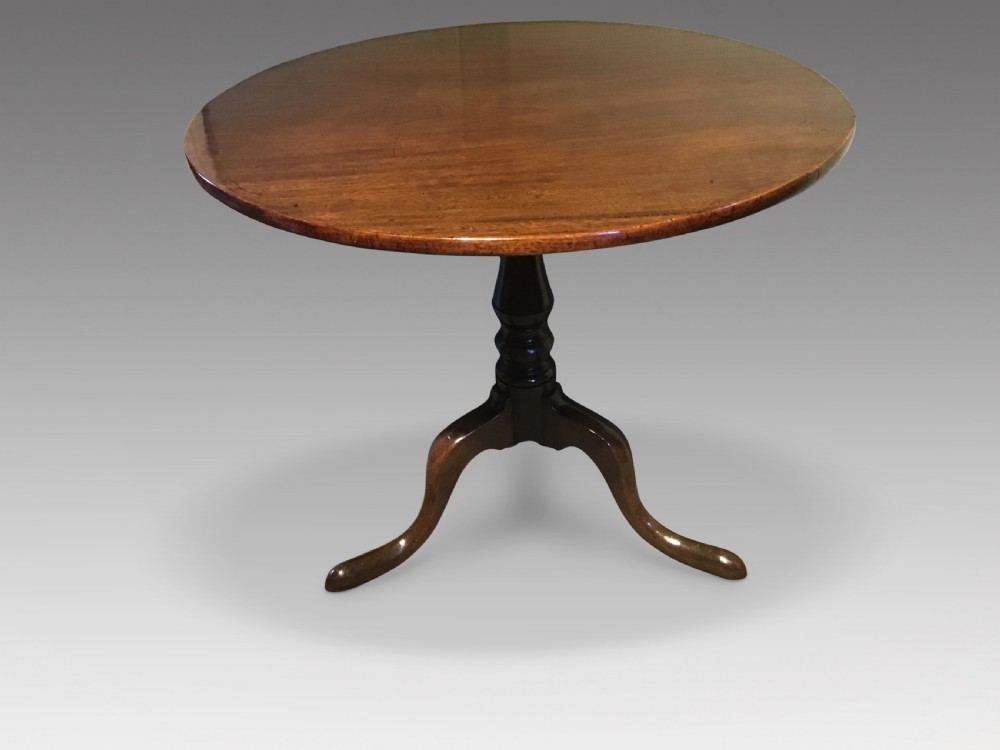 A Georgian mahogany tripod table with a circular tilt-top raised on a turned central pedestal and three cabriole legs. View II