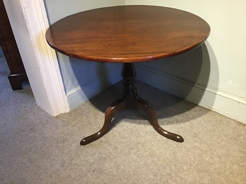 A Georgian mahogany tripod table with a circular tilt-top raised on a turned central pedestal and three cabriole legs. View III