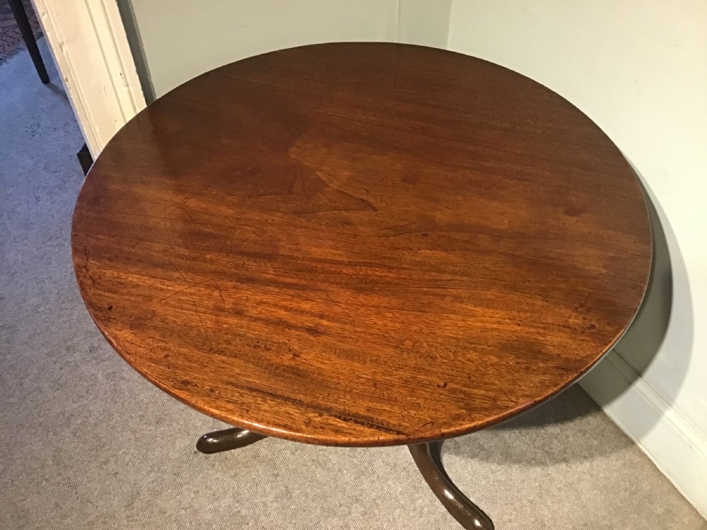 A Georgian mahogany tripod table with a circular tilt-top raised on a turned central pedestal and three cabriole legs. View IV
