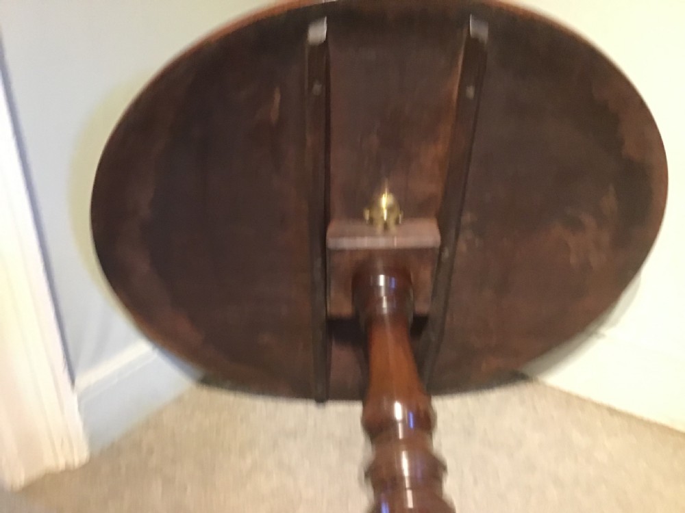 A Georgian mahogany tripod table with a circular tilt-top raised on a turned central pedestal and three cabriole legs. View VII