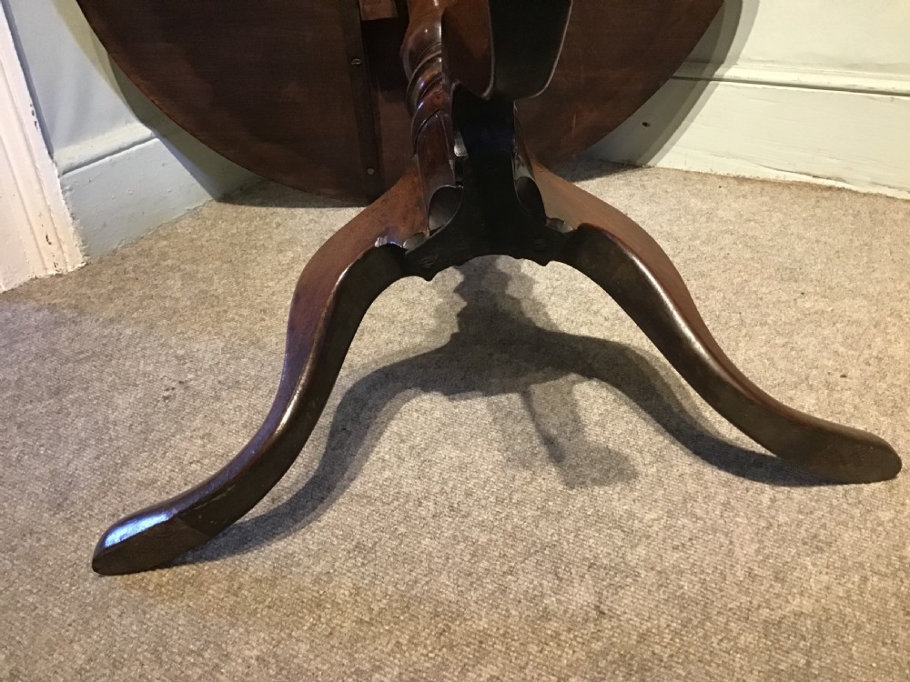 A Georgian mahogany tripod table with a circular tilt-top raised on a turned central pedestal and three cabriole legs. View VIII