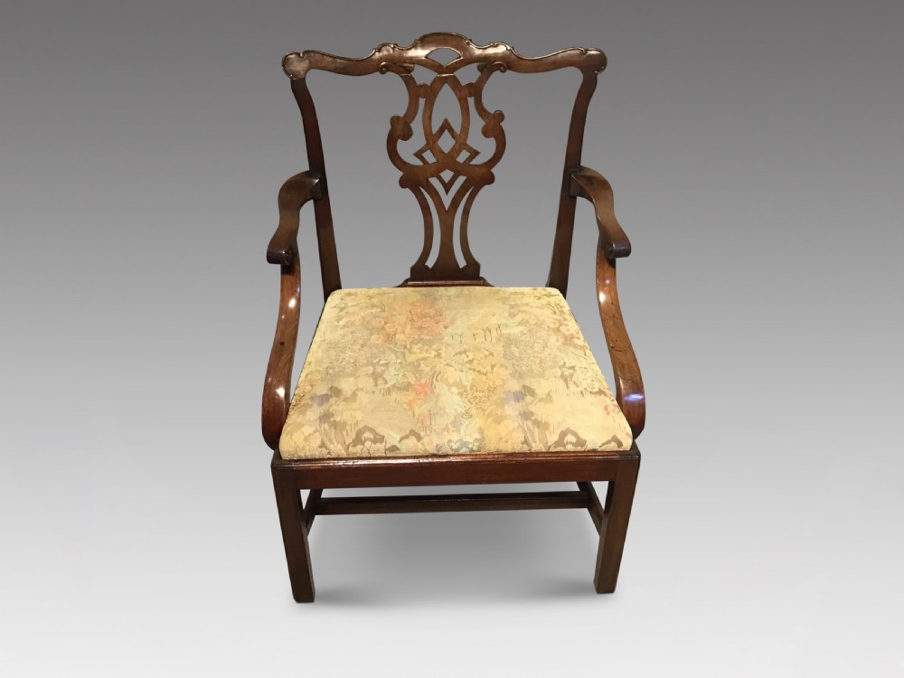 An antique mahogany elbow chair featuring a carved pierced back splat, curved arms, and a soft beige floral tapestry seat. View II