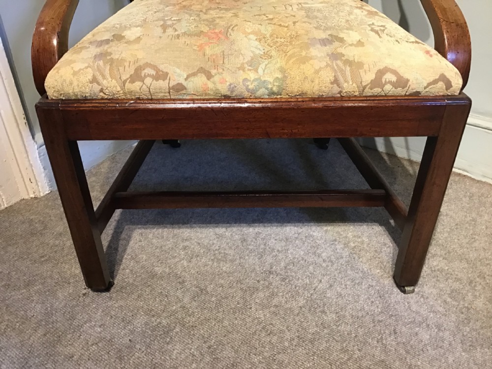 An antique mahogany elbow chair featuring a carved pierced back splat, curved arms, and a soft beige floral tapestry seat. View V