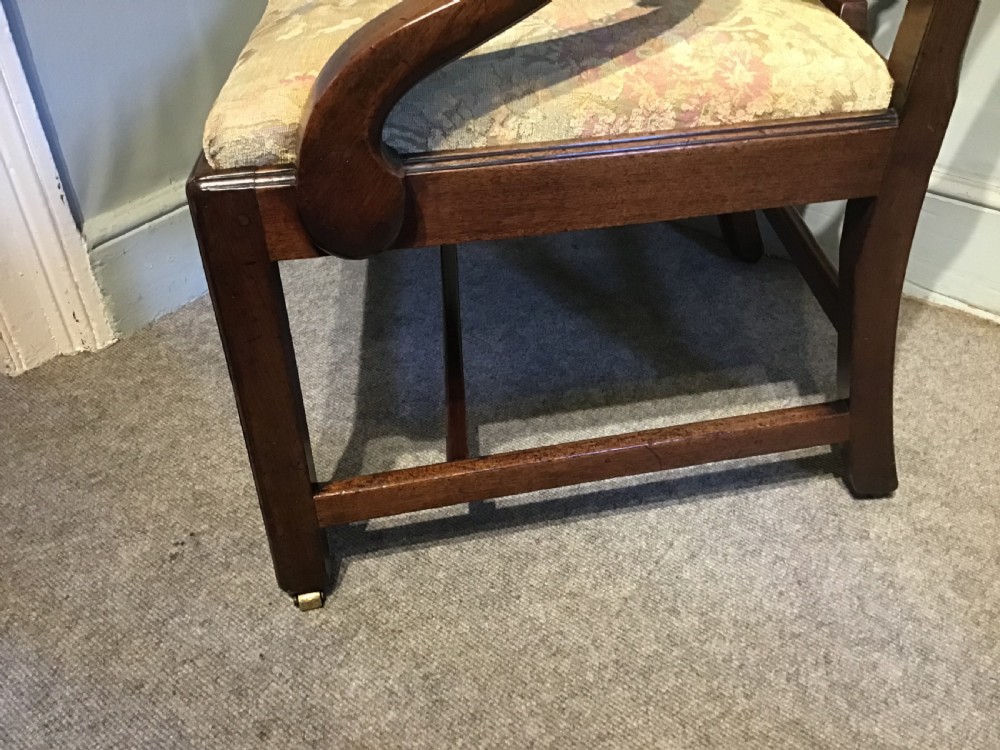 An antique mahogany elbow chair featuring a carved pierced back splat, curved arms, and a soft beige floral tapestry seat. View VI