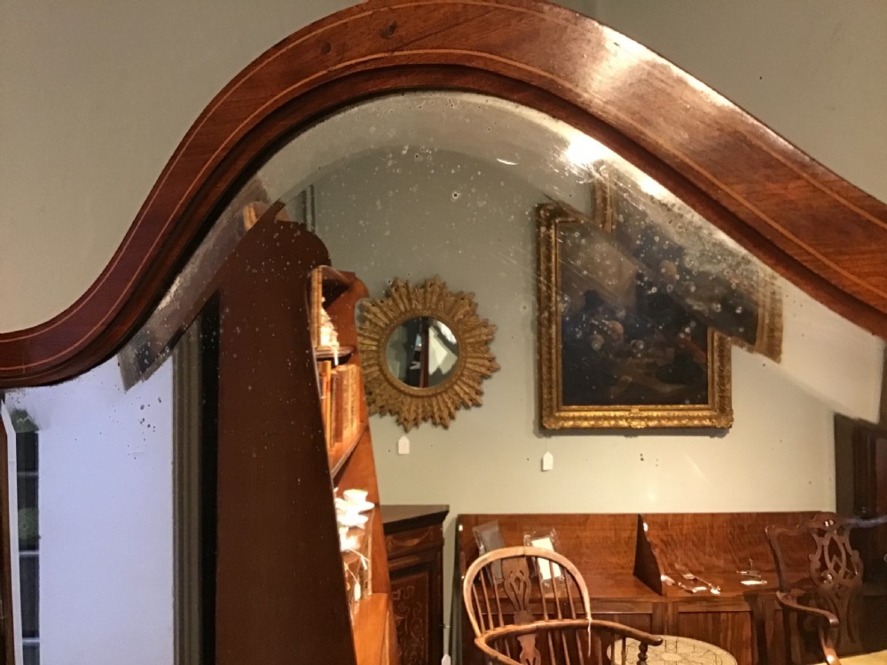 An antique mahogany cheval mirror featuring a shield-shaped tilting glass frame supported by curved uprights on splayed legs with brass castors. View III