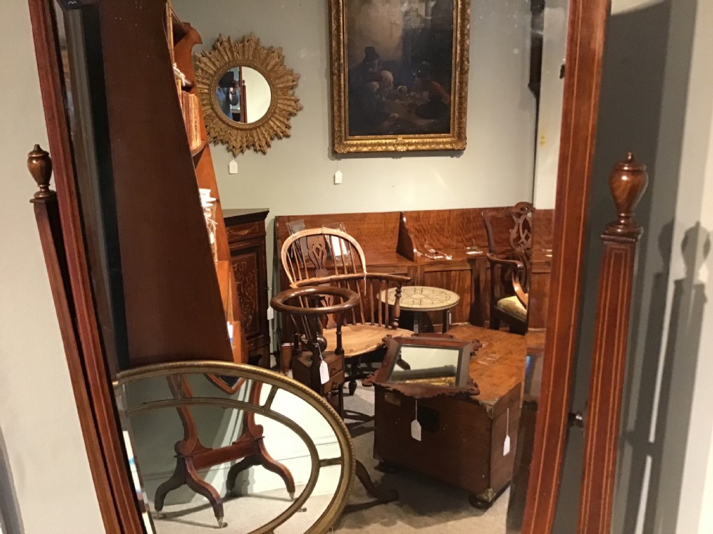 An antique mahogany cheval mirror featuring a shield-shaped tilting glass frame supported by curved uprights on splayed legs with brass castors. View IV
