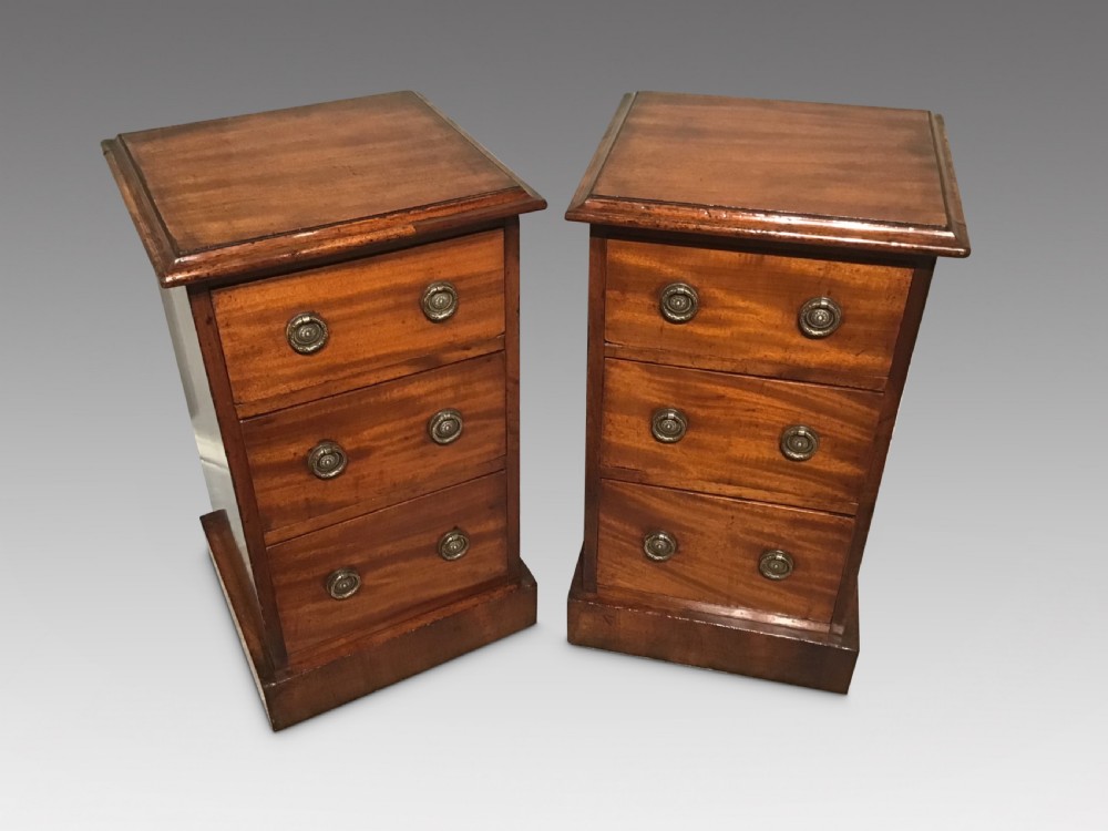 A pair of narrow antique mahogany bedside chests, each featuring three drawers with round brass ring handles and a plinth base. View II