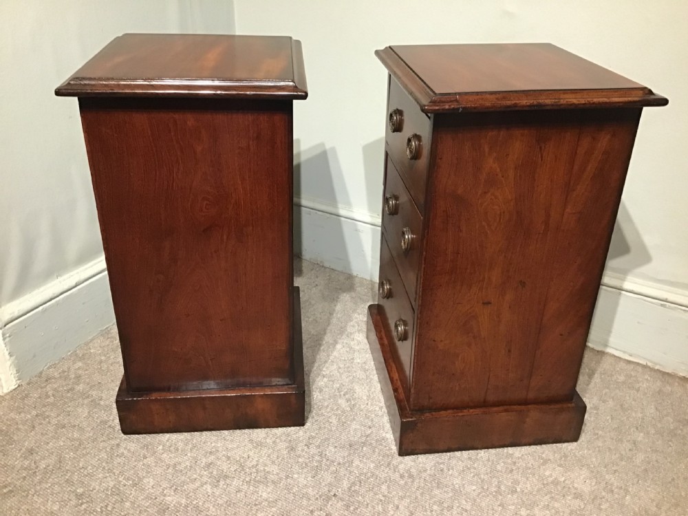 A pair of narrow antique mahogany bedside chests, each featuring three drawers with round brass ring handles and a plinth base. View V
