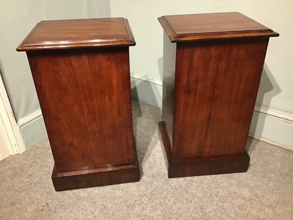 A pair of narrow antique mahogany bedside chests, each featuring three drawers with round brass ring handles and a plinth base. View VI