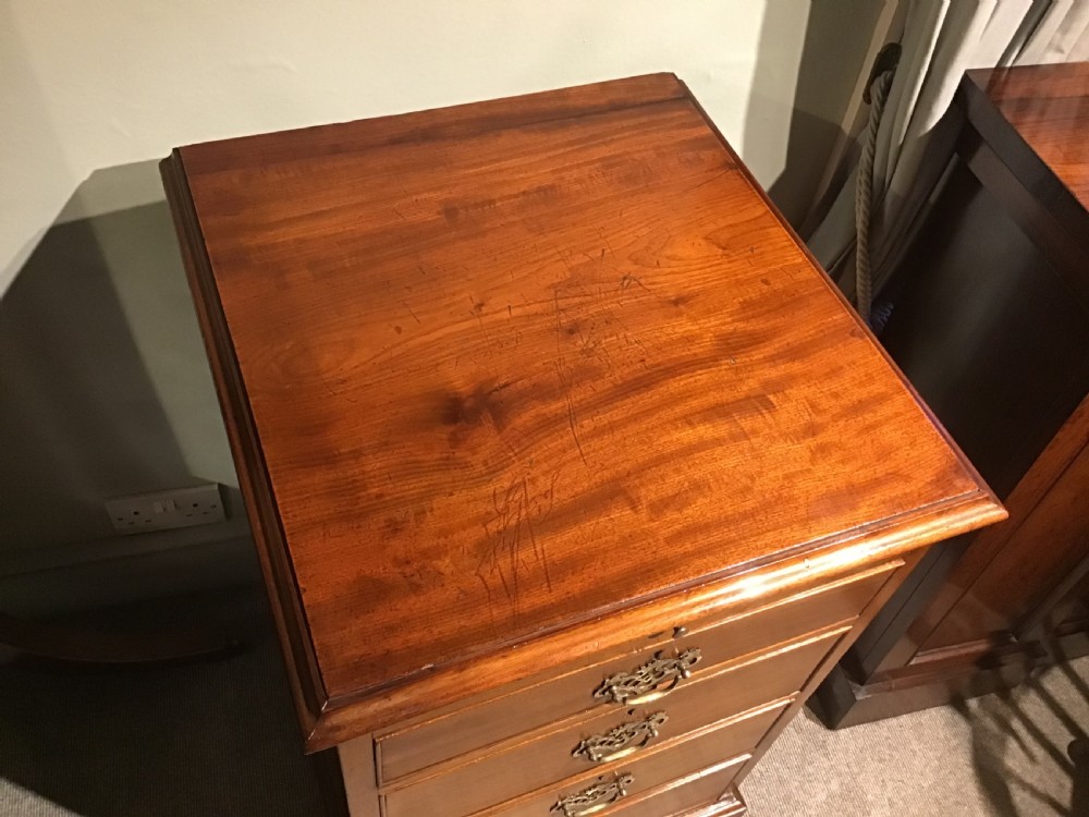 A narrow Georgian-style warm brown mahogany chest of drawers featuring four graduated drawers with pierced brass handles, a brushing slide, and bracket feet. View III