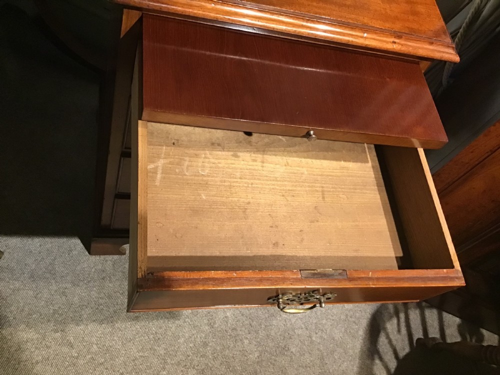A narrow Georgian-style warm brown mahogany chest of drawers featuring four graduated drawers with pierced brass handles, a brushing slide, and bracket feet. View IX
