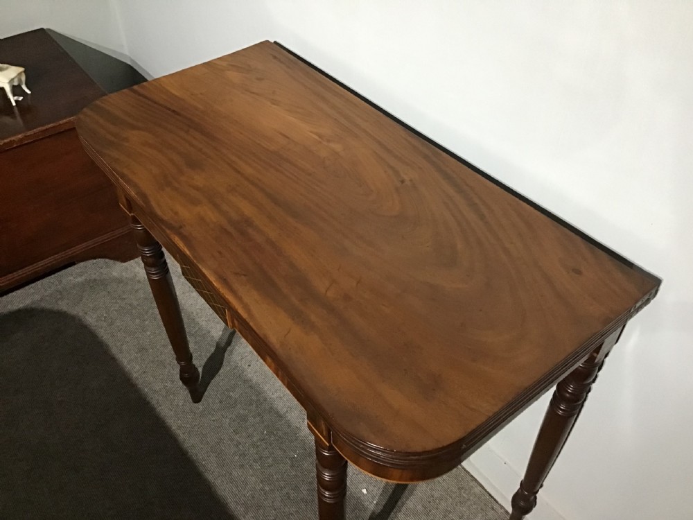 An antique dark mahogany fold-over tea table featuring turned legs and a central inlaid geometric motif on the front apron. View III