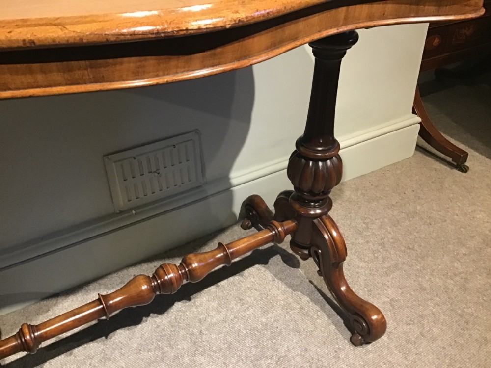 A Victorian mahogany side table featuring a serpentine-shaped top supported by carved baluster pedestals and a turned stretcher. View IV