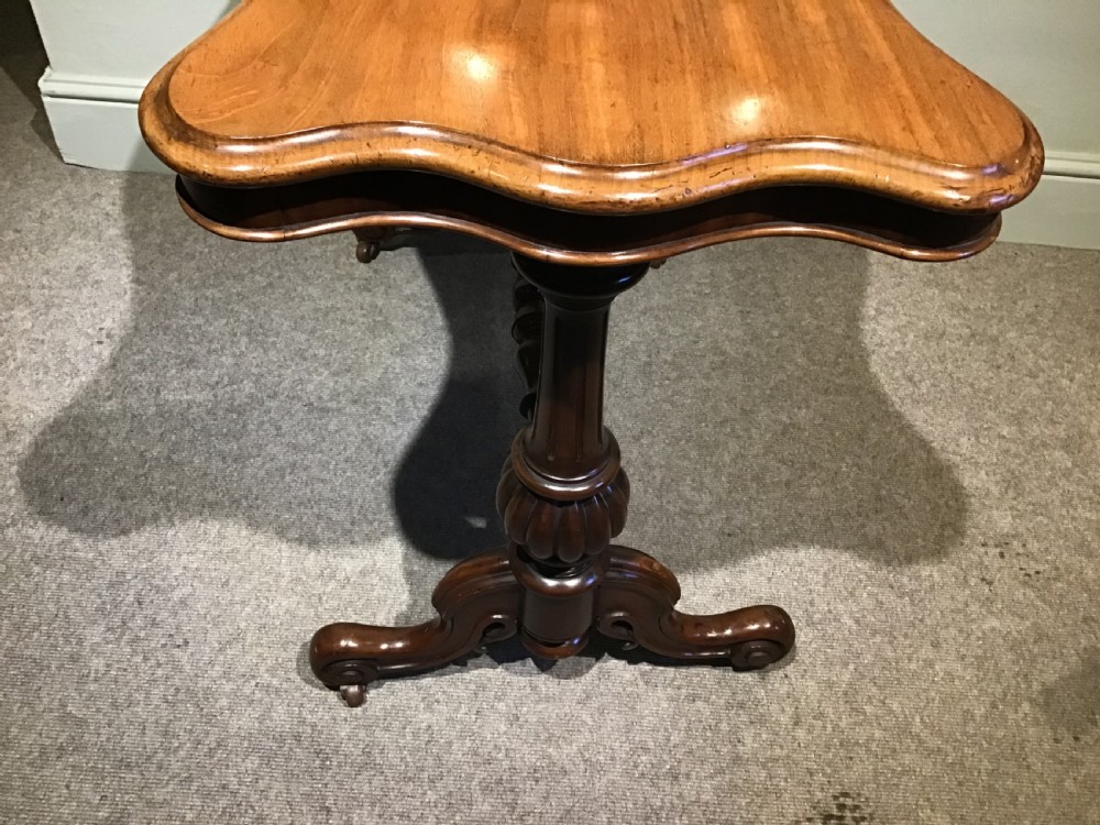 A Victorian mahogany side table featuring a serpentine-shaped top supported by carved baluster pedestals and a turned stretcher. View V