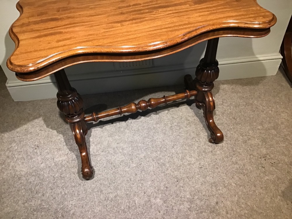 A Victorian mahogany side table featuring a serpentine-shaped top supported by carved baluster pedestals and a turned stretcher. View VI