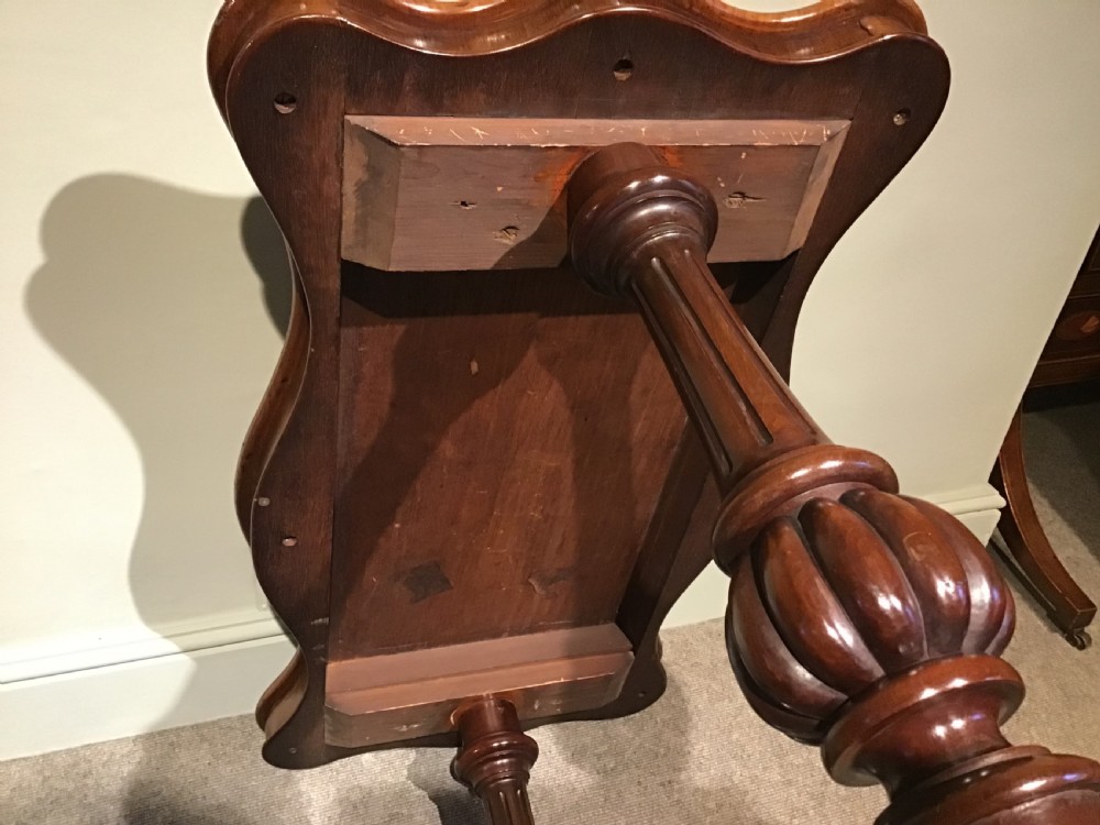 A Victorian mahogany side table featuring a serpentine-shaped top supported by carved baluster pedestals and a turned stretcher. View VII