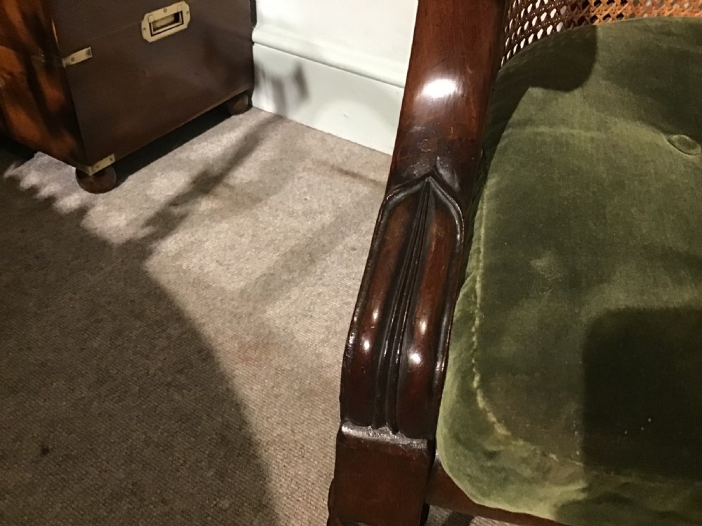 A Regency mahogany bergere armchair featuring hand-woven cane panels, reeded turned front legs on brass castors, and a buttoned green velvet seat cushion. View VIII
