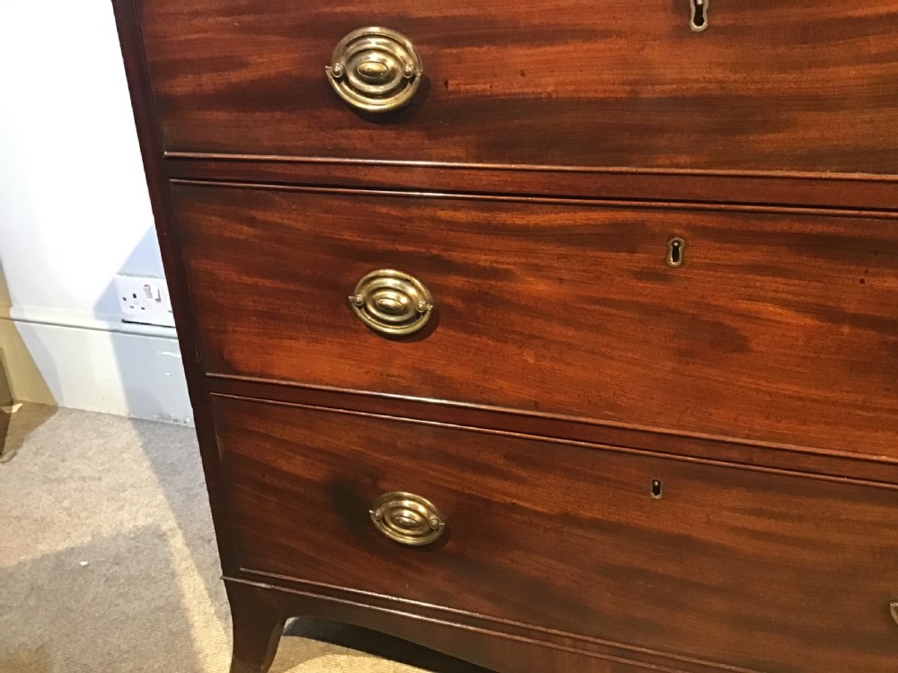 An antique mahogany chest of drawers featuring three drawers with brass oval handles and bracket feet. View VI
