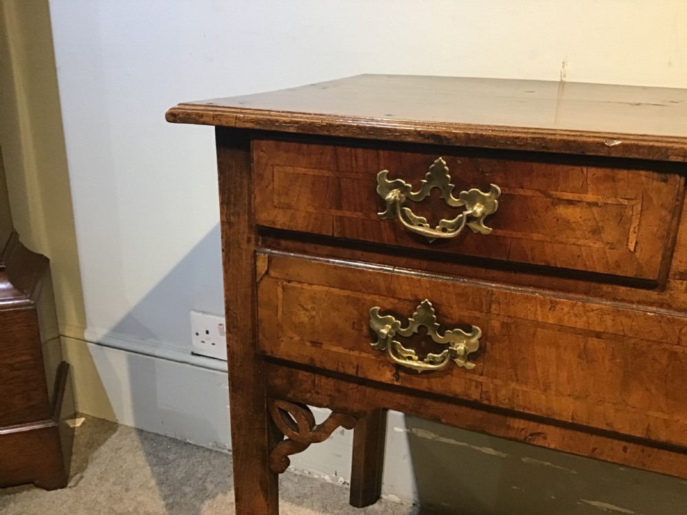 An 18th-century style antique walnut lowboy table featuring three drawers with decorative brass handles and fretwork corner brackets. View VI