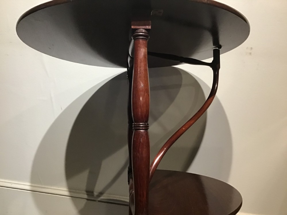 An antique dark mahogany folding occasional table featuring a round top, lower semi-circular shelf, turned uprights, and curved feet. View VIII