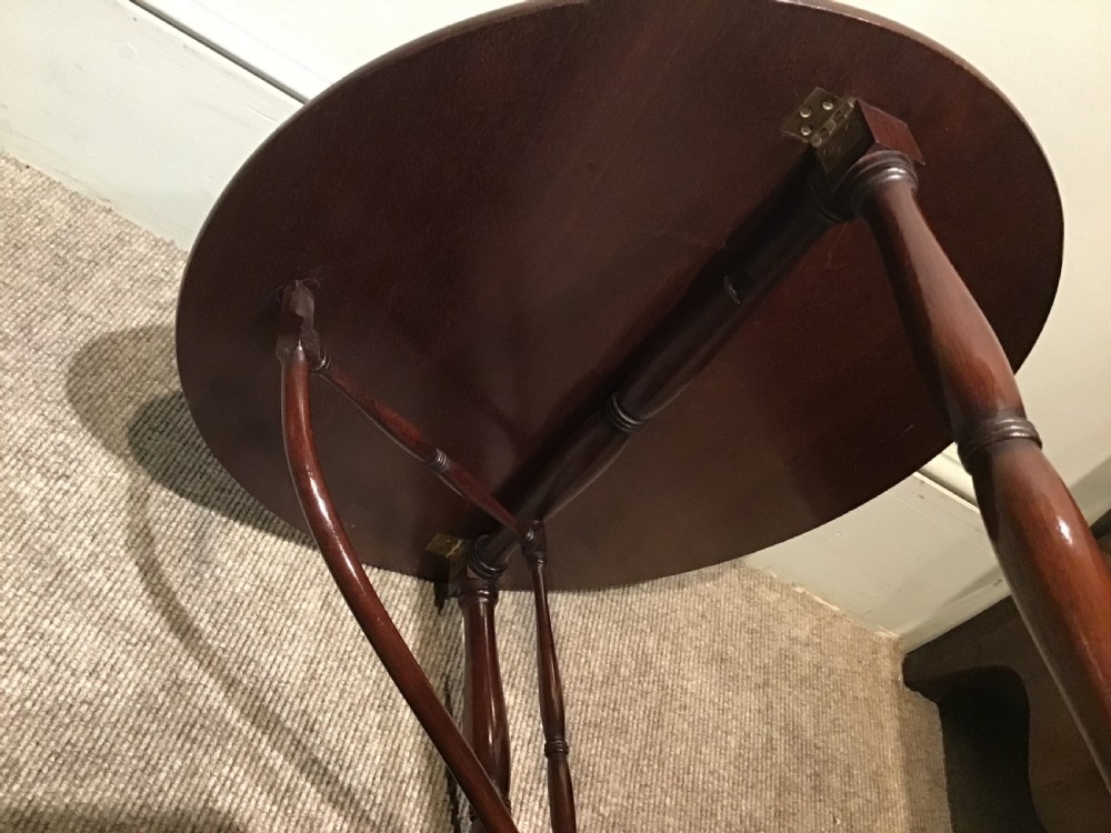 An antique dark mahogany folding occasional table featuring a round top, lower semi-circular shelf, turned uprights, and curved feet. View XII