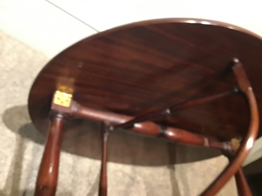 An antique dark mahogany folding occasional table featuring a round top, lower semi-circular shelf, turned uprights, and curved feet. View XIII