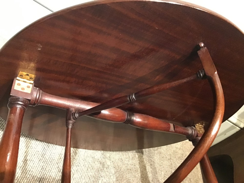 An antique dark mahogany folding occasional table featuring a round top, lower semi-circular shelf, turned uprights, and curved feet. View XIV