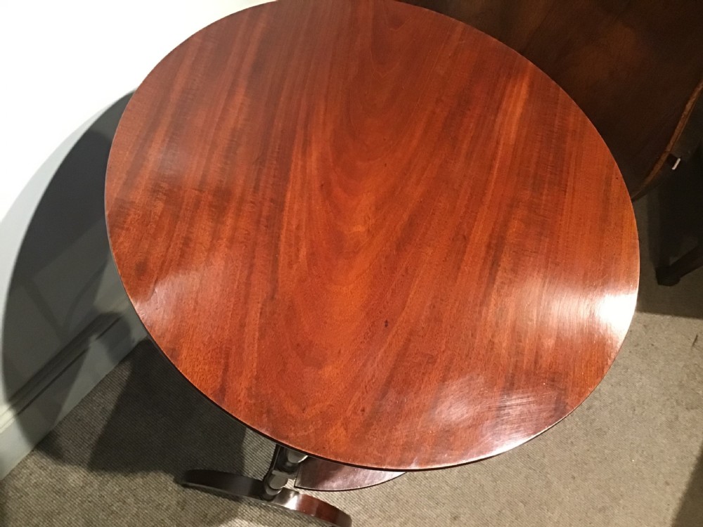 An antique dark mahogany folding occasional table featuring a round top, lower semi-circular shelf, turned uprights, and curved feet. View XVII