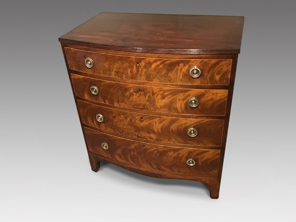 A mahogany bow-front chest of drawers featuring four graduated drawers with flame veneers, brass ring handles, and splayed bracket feet.