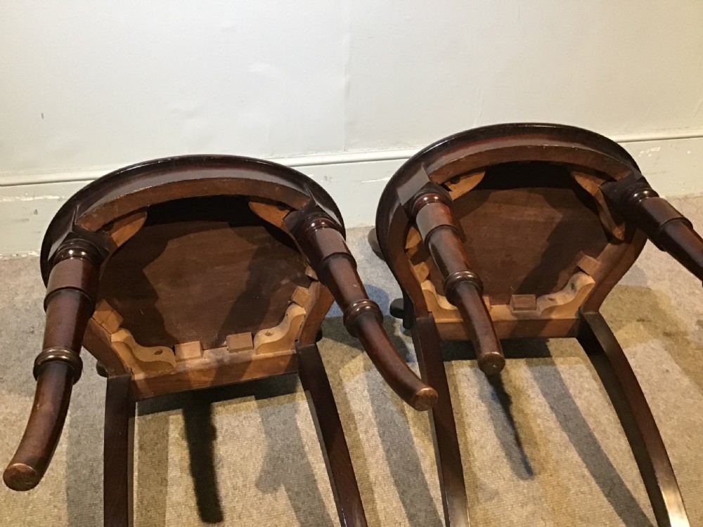 A pair of antique dark mahogany hall chairs featuring carved scroll backs, solid wood seats, and turned front legs. View XIII