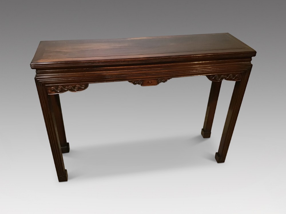 A narrow dark brown timber Chinese altar table featuring carved corner spandrels, reeded square legs, and a rectangular panelled top. View II