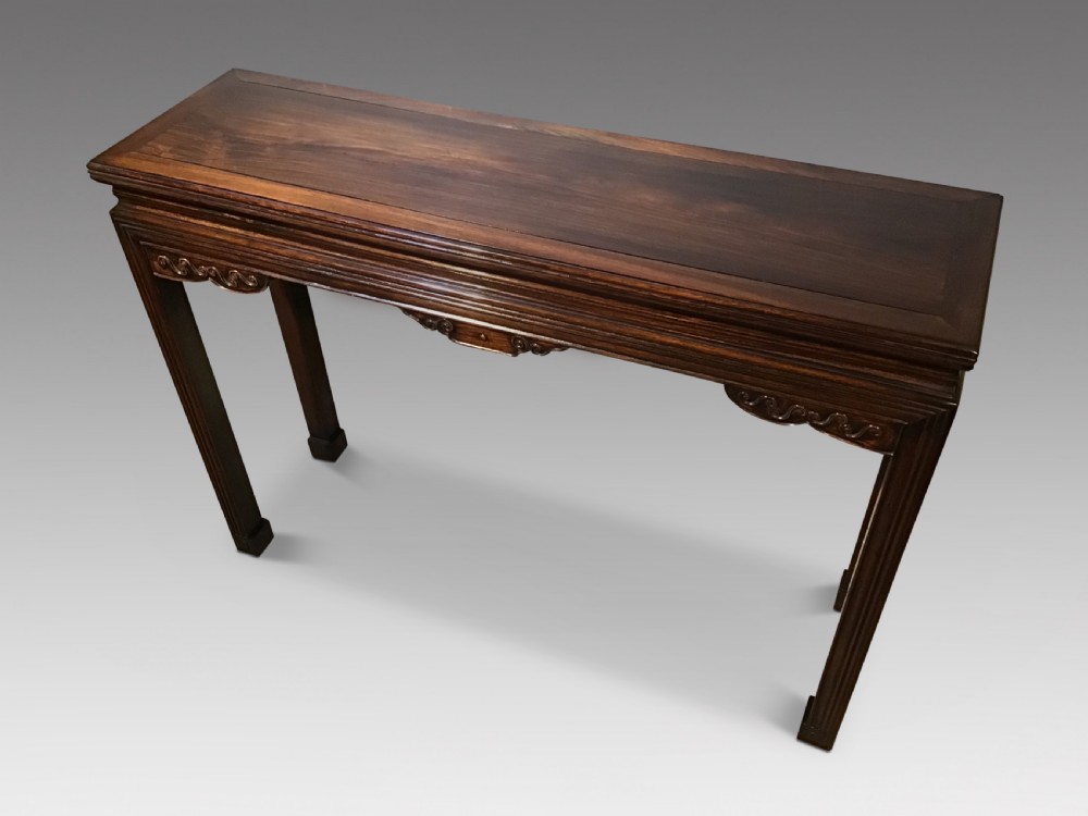 A narrow dark brown timber Chinese altar table featuring carved corner spandrels, reeded square legs, and a rectangular panelled top. View III
