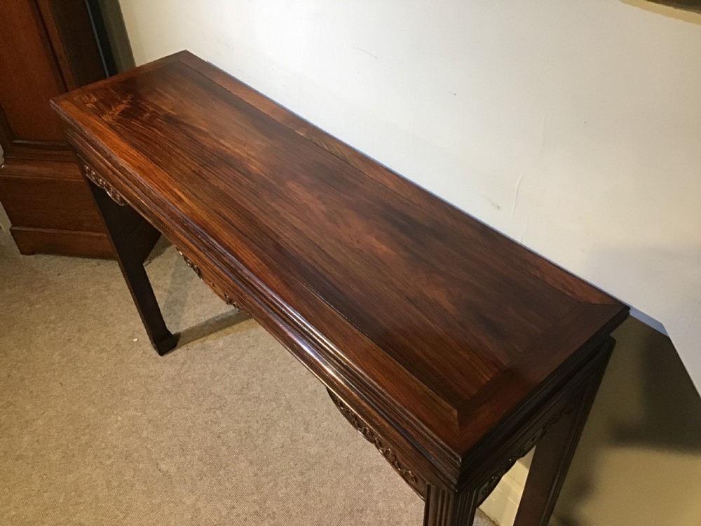 A narrow dark brown timber Chinese altar table featuring carved corner spandrels, reeded square legs, and a rectangular panelled top. View IV
