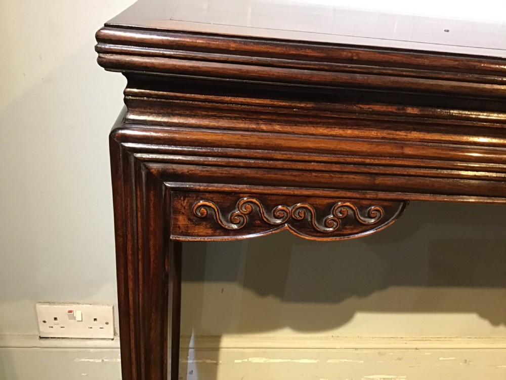 A narrow dark brown timber Chinese altar table featuring carved corner spandrels, reeded square legs, and a rectangular panelled top. View V