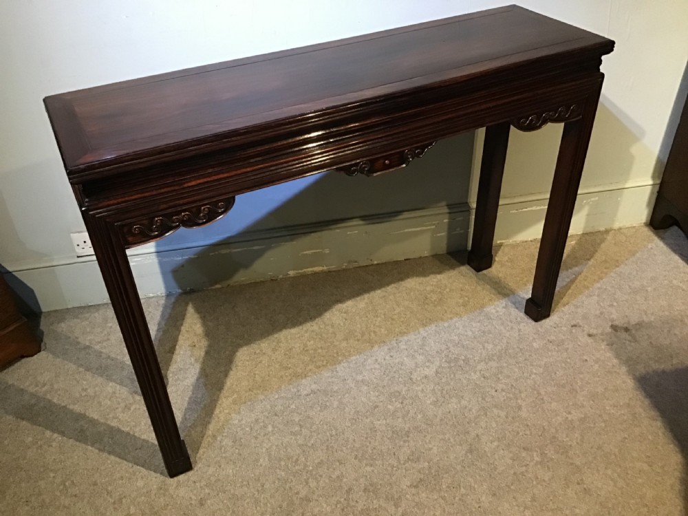 A narrow dark brown timber Chinese altar table featuring carved corner spandrels, reeded square legs, and a rectangular panelled top. View XIII