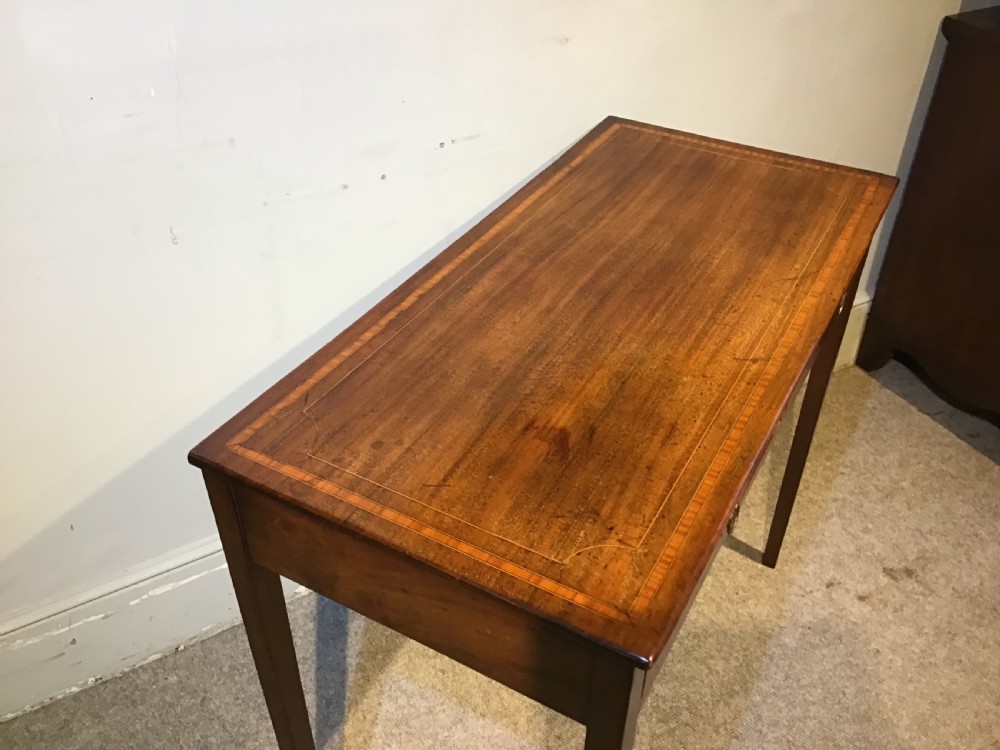 An antique Georgian mahogany side table featuring two drawer compartments with brass ring handles, boxwood inlaid border detail, and four square tapered legs. View IV