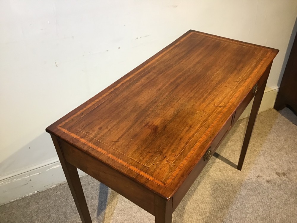 An antique Georgian mahogany side table featuring two drawer compartments with brass ring handles, boxwood inlaid border detail, and four square tapered legs. View V