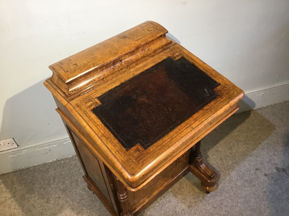 A Victorian burr walnut Davenport desk featuring a sloped leather writing surface, inlaid wood corner detailing, turned front supports, and a top stationery compartment. View II