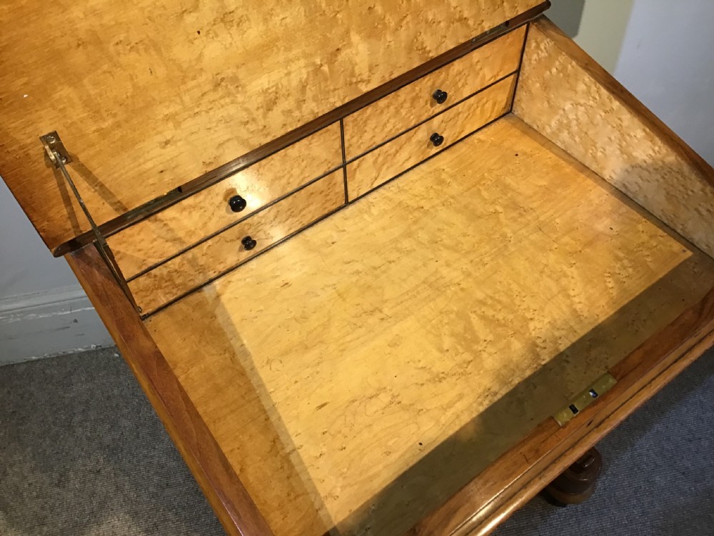 A Victorian burr walnut Davenport desk featuring a sloped leather writing surface, inlaid wood corner detailing, turned front supports, and a top stationery compartment. View VII