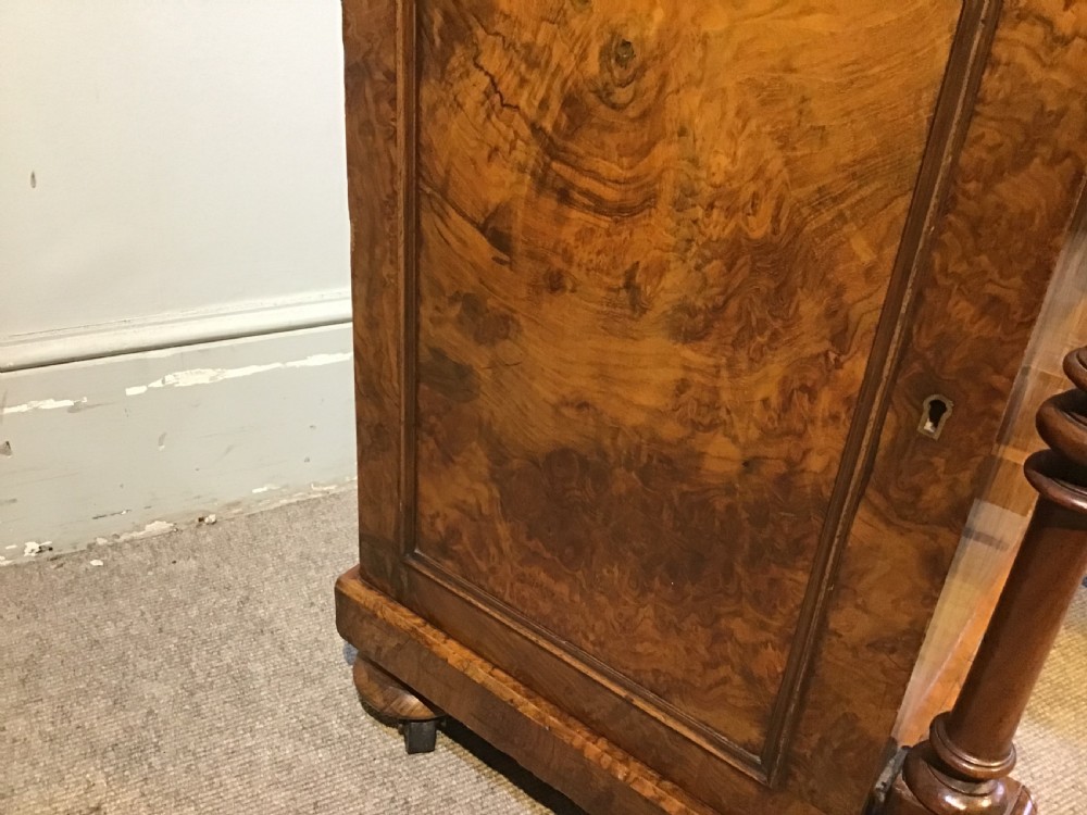 A Victorian burr walnut Davenport desk featuring a sloped leather writing surface, inlaid wood corner detailing, turned front supports, and a top stationery compartment. View X