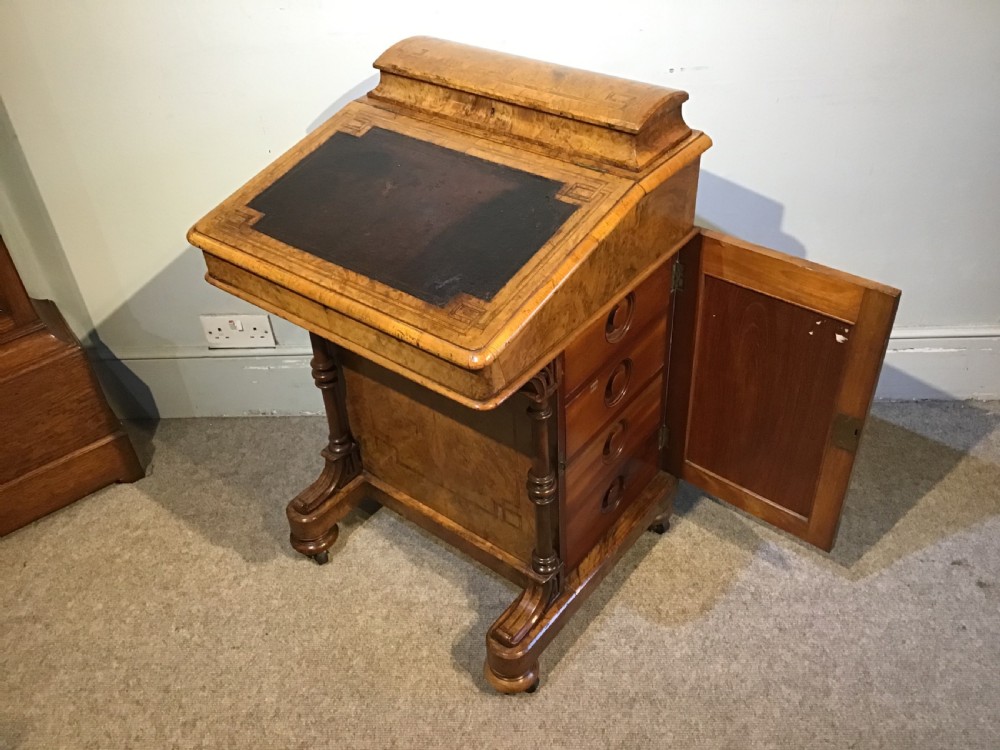 A Victorian burr walnut Davenport desk featuring a sloped leather writing surface, inlaid wood corner detailing, turned front supports, and a top stationery compartment. View XI