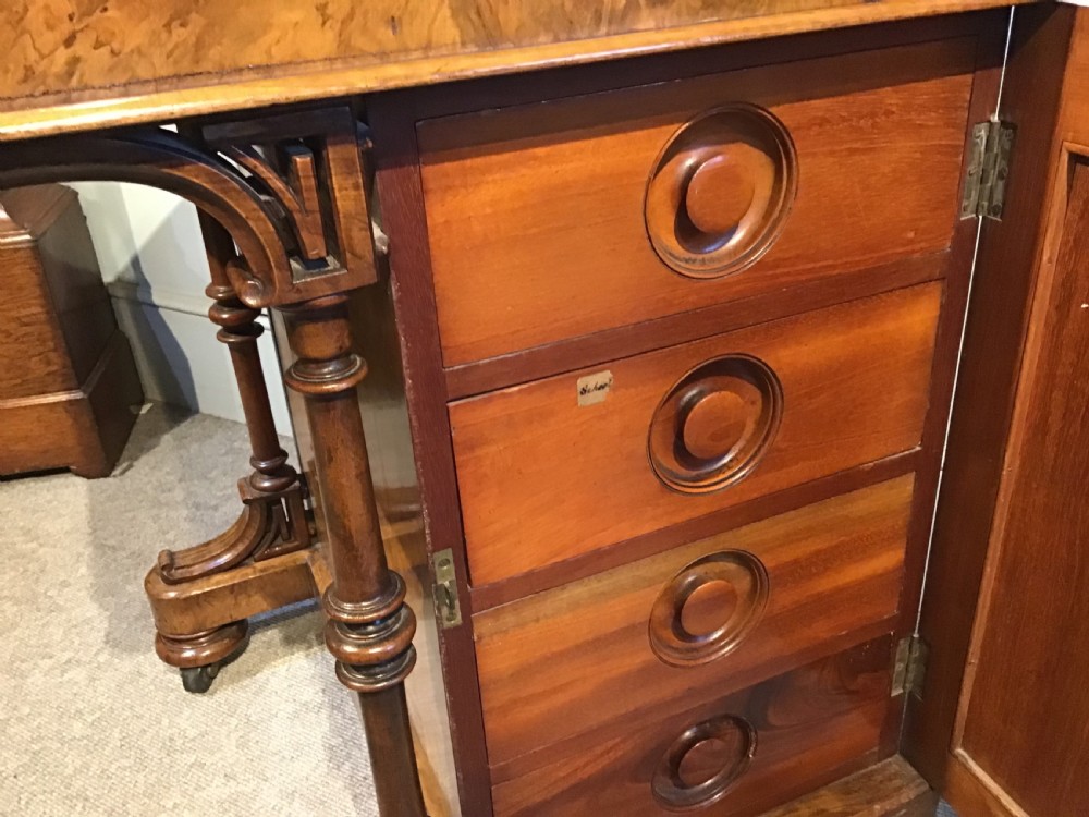 A Victorian burr walnut Davenport desk featuring a sloped leather writing surface, inlaid wood corner detailing, turned front supports, and a top stationery compartment. View XII
