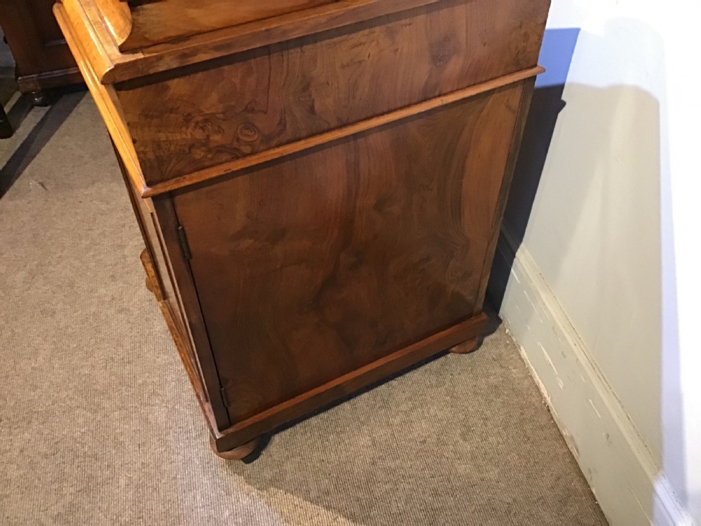 A Victorian burr walnut Davenport desk featuring a sloped leather writing surface, inlaid wood corner detailing, turned front supports, and a top stationery compartment. View XV