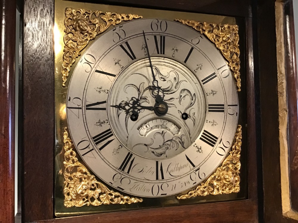 A Georgian oak eight-day longcase clock featuring an engraved brass dial, fluted hood columns, and a tall timber trunk resting on bracket feet. View XI