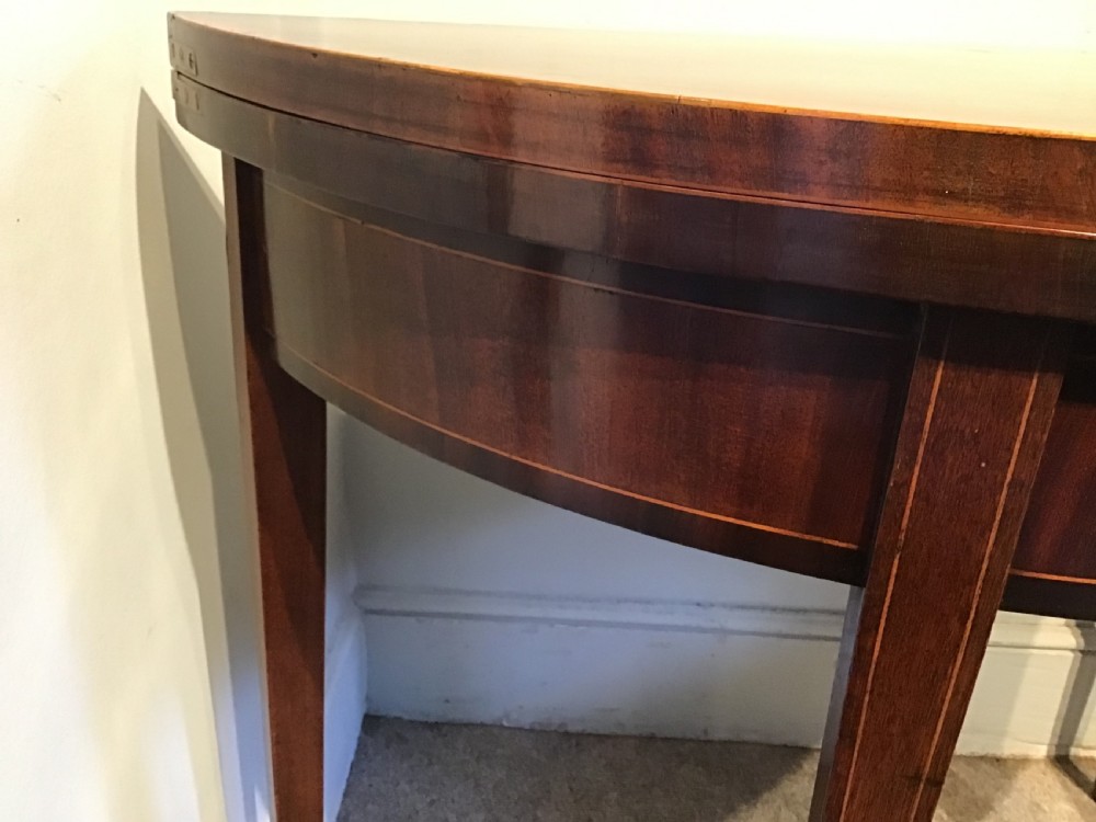 A Georgian dark mahogany demi-lune console table featuring a semicircular top with a central fan inlay motif and square tapered legs. View IV